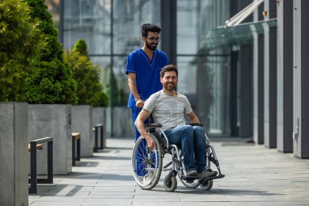 Photo for Disability. Brunette male nurse rolling a wheelchair with a patient - Royalty Free Image
