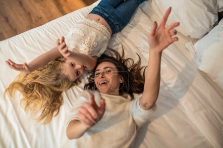 Téléchargez les photos : Belle femme et sa fille dans la chambre à coucher avec bougie s'amuser ensemble - en image libre de droit