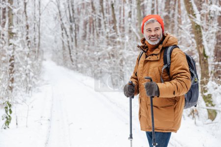 Walk with sticks. Man having a walk with scandinavian sticks in a snowy forest