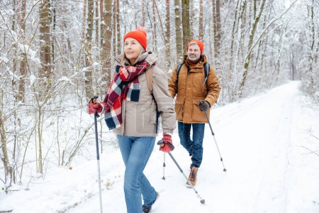 Leisure and active rest. A couple having a walk in a winter forest and looking contented