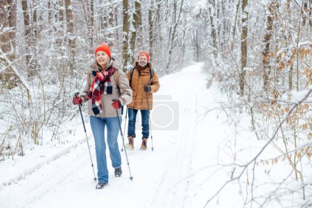Ocio y descanso activo. Una pareja dando un paseo en un bosque de invierno y buscando contentos
