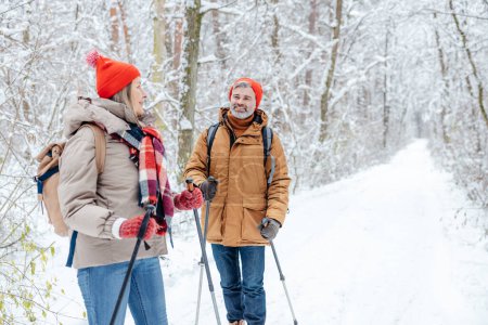 Photo for Leisure and active rest. A couple having a walk in a winter forest and looking contented - Royalty Free Image