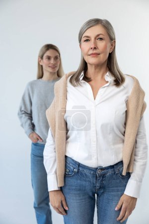 Photo for Mom and daughter. Confident mature woman standing, her daughter behind her - Royalty Free Image