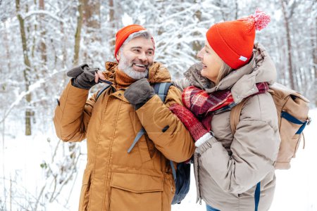 Téléchargez les photos : Promenade hivernale. Couple mature dans une forêt d'hiver se sentant heureux - en image libre de droit