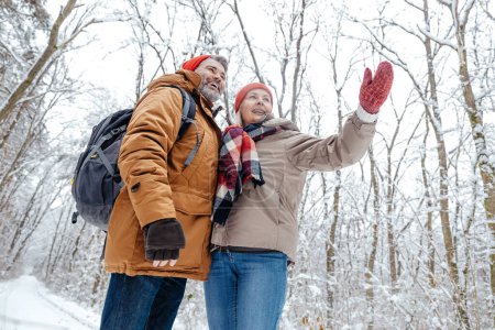 Winter. Mature couple in a snowy forest feeling excited