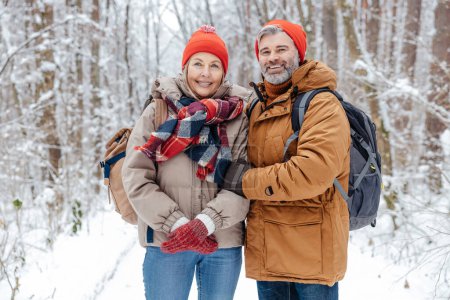 Photo for Happy couple. Happy mature couple in a snowy forest feeling wonderful - Royalty Free Image