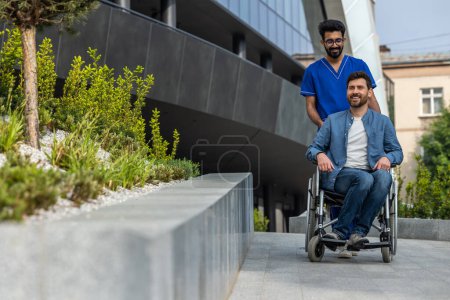 Photo for Walk on wheelchair. Male nurse carrying a wheelchair with a male patient - Royalty Free Image