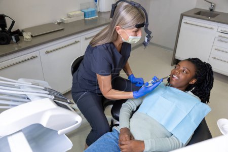 Foto de Dentista mujer inyectando anestesia a la paciente en el hospital - Imagen libre de derechos