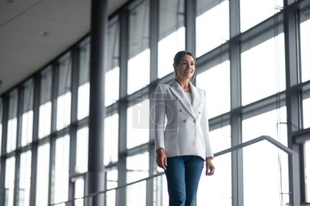 Photo for Stylish woman. Good-looking woman in white jacket and jeans in the office building - Royalty Free Image