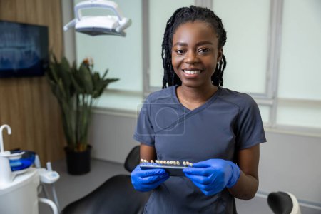 Téléchargez les photos : Femme dentiste tenant le tableau guide de l'ombre des dents dentaires dans son bureau médical - en image libre de droit