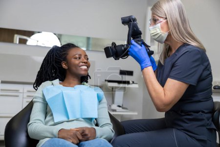 Téléchargez les photos : Dentiste faisant la photo de la bouche du patient après le traitement de soins buccodentaires - en image libre de droit