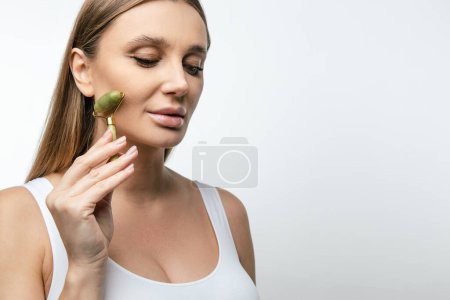 Photo for Face massage. Blonde woman making face massage with a roller - Royalty Free Image