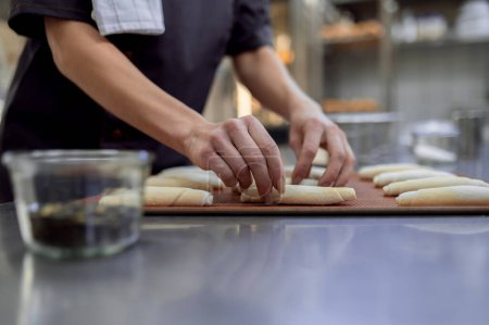 Téléchargez les photos : Femme méconnaissable boulanger croissant cuisson dans boulangerie professionnelle - en image libre de droit