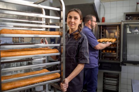 Photo for Man and woman in bakery shop preparing French baguettes - Royalty Free Image