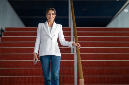 Photo for Business woman. Woman in white jacket near the red stairs in the office building - Royalty Free Image