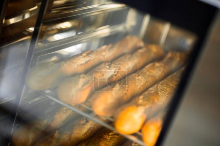 Photo for Cooking fresh crispy baguettes in oven at commercial bakery - Royalty Free Image