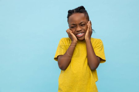 Foto de Frustrado niño afroamericano cubriendo orejas aisladas sobre fondo azul - Imagen libre de derechos