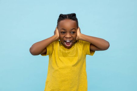 Foto de Emocionado niño de piel oscura que sufre de sonido fuerte aislado sobre fondo azul - Imagen libre de derechos
