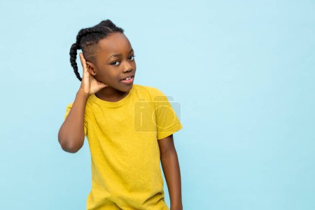Photo for Serious curious dark- skinned little boy hearing something isolated over blue background - Royalty Free Image