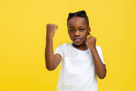 Dangerous dark-skinned little boy boxing with hand isolated over yellow background