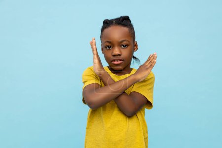 Strict African American little boy showing x-sign gesture isolated over blue background