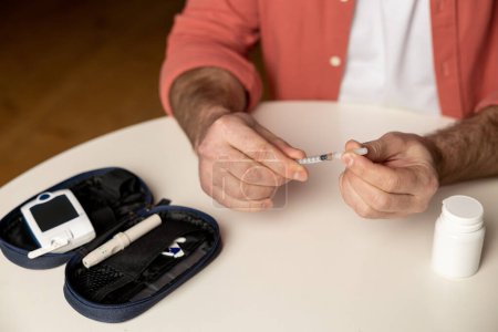 Foto de Hombre diabético irreconocible con inyección de jeringa de insulina sentado en la mesa en casa - Imagen libre de derechos