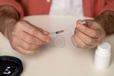 Photo for Unknown diabetic man with syringe preparing for insulin injection sitting in home interior - Royalty Free Image