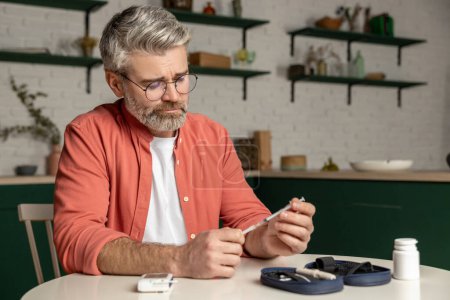 Téléchargez les photos : Homme diabétique avec seringue préparant l'injection d'insuline assis à l'intérieur de la maison - en image libre de droit