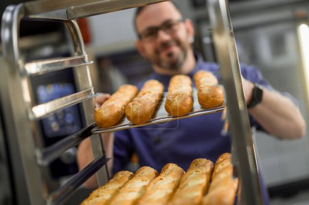 Foto de Panadero profesional en panadería con pan baguette en panadería - Imagen libre de derechos