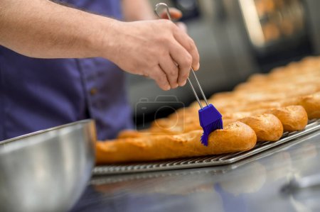 Photo for Unrecognizable man baker baking French baguette bread at baking manufacture factory - Royalty Free Image