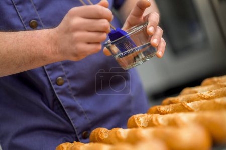 Téléchargez les photos : Homme méconnaissable boulanger pain baguette français à l'usine de fabrication de boulangerie - en image libre de droit