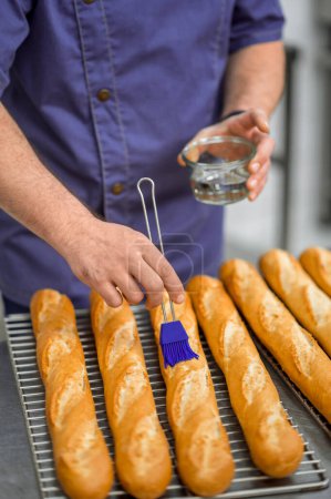 Foto de Hombre irreconocible panadero hornear y vender sabrosos panes en panadería - Imagen libre de derechos
