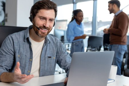 Téléchargez les photos : Opérateur de centre d'appels professionnel dans casque travaillant sur ordinateur portable dans l'espace de coworking - en image libre de droit