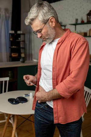 Foto de Hombre insalubre con jeringa que hace insulina inyectable solo en casa - Imagen libre de derechos