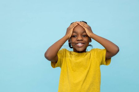 Téléchargez les photos : Heureux petit garçon afro-américain voit quelque chose de surpris isolé sur fond bleu - en image libre de droit