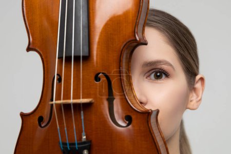 Photo for Closeup of young woman hiding her face with violin isolated over white background - Royalty Free Image