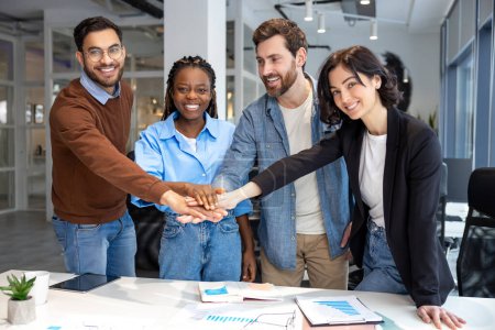 Photo for Group of diverse businesspeople holding hands working together in modern workspace in office - Royalty Free Image