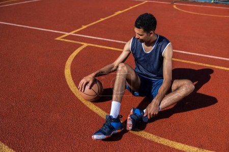 Photo for Handsome basketball player sitting on outdoor summer court - Royalty Free Image