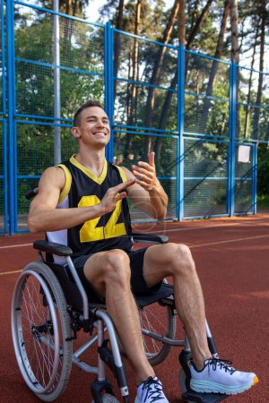 Homme sportif avec handicap man?uvrant en fauteuil roulant se livrant à l'entraînement de basket-ball sur le court d'été.