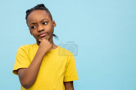 Téléchargez les photos : Sérieux garçon. Mignon garçon afro-américain en tshirt jaune à l'air sérieux - en image libre de droit