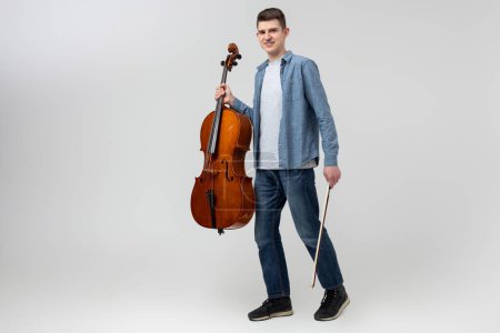 bel homme musicien jouer violoncelle sur concert isolé sur fond gris clair