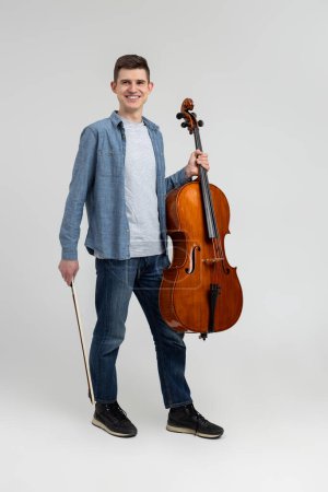 Jeune homme portant des vêtements décontractés jouant violoncelle isolé sur fond blanc