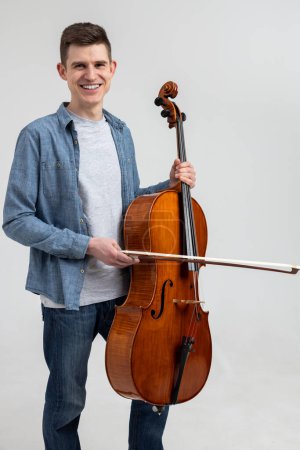 Photo for Young man wearing casual clothing playing cello isolated over white background - Royalty Free Image