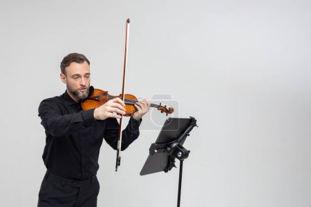 Foto de Músico profesional tocando violín realizando concierto de pie aislado sobre fondo gris claro - Imagen libre de derechos
