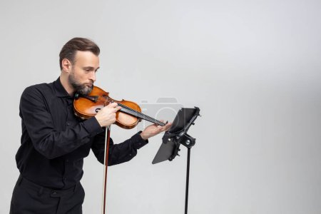 Téléchargez les photos : Musicien professionnel jouant du violon en concert debout isolé sur fond gris clair - en image libre de droit