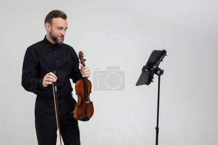 Foto de Hombre guapo sosteniendo un violín en sus manos tocando música clásica aislada sobre fondo blanco - Imagen libre de derechos