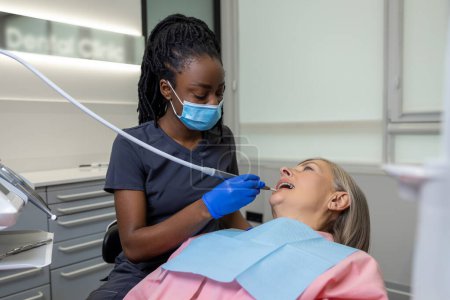 Dentist office. Dark-skinned female dentist working with the patient
