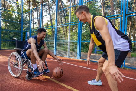 Foto de Atleta con entrenamiento de discapacidad y ejercicio con un amigo en la cancha de baloncesto al aire libre - Imagen libre de derechos