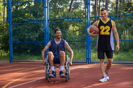 Téléchargez les photos : Joueur de basketball en fauteuil roulant homme jouant compétition de match avec un ami sur le terrain extérieur - en image libre de droit