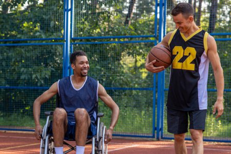 Téléchargez les photos : Athlète handicapé s'entraînant et faisant de l'exercice avec un ami sur un terrain de basketball extérieur - en image libre de droit